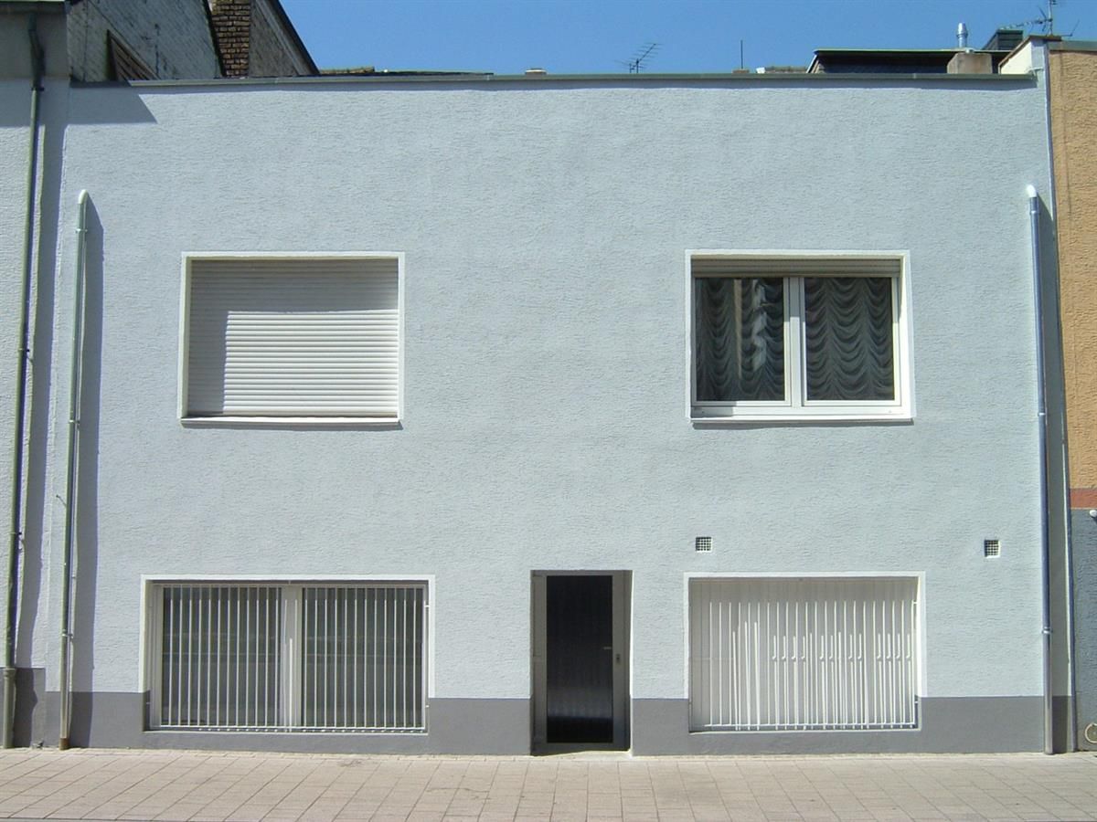 Ein weißes Gebäude mit einer Tür und zwei Fenstern