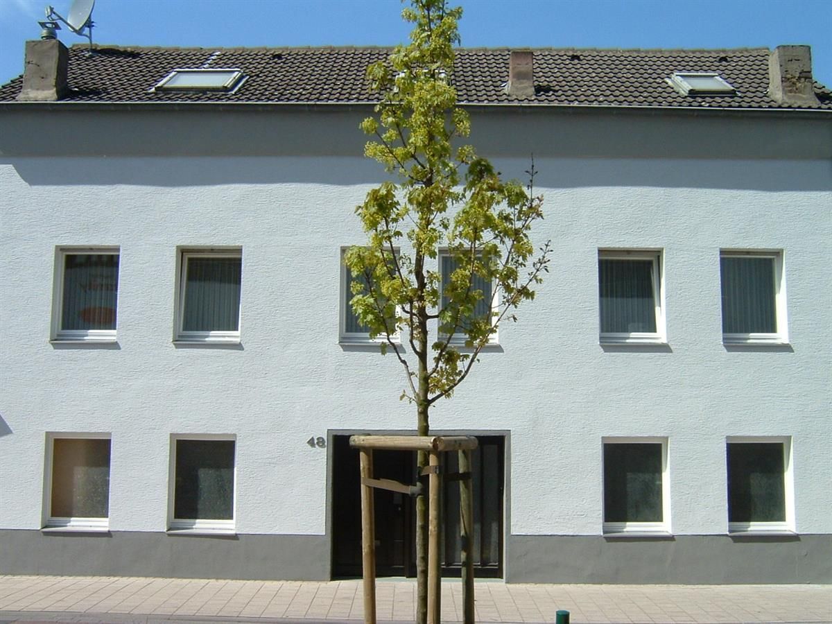 Ein weißes Gebäude mit einem Baum davor