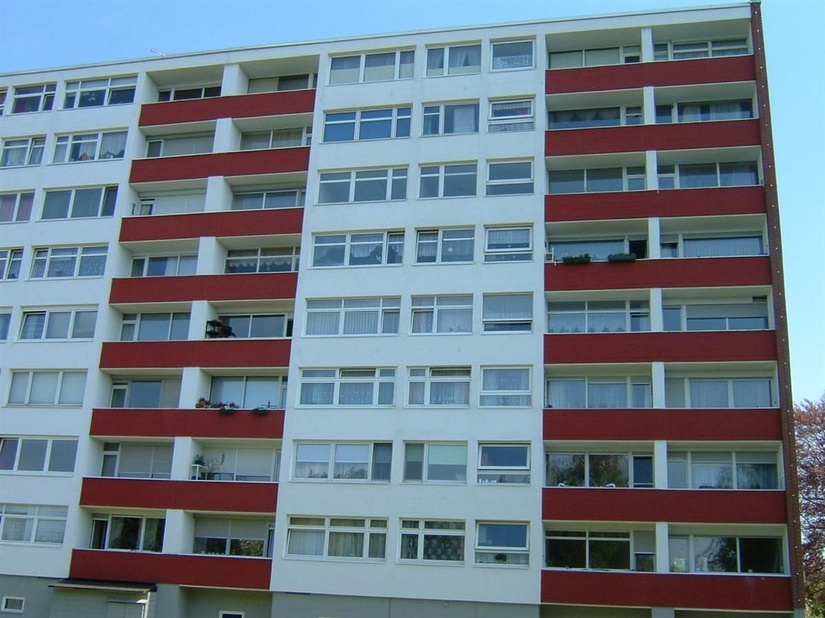 Ein großes weißes Gebäude mit roten Balkonen vor einem blauen Himmel