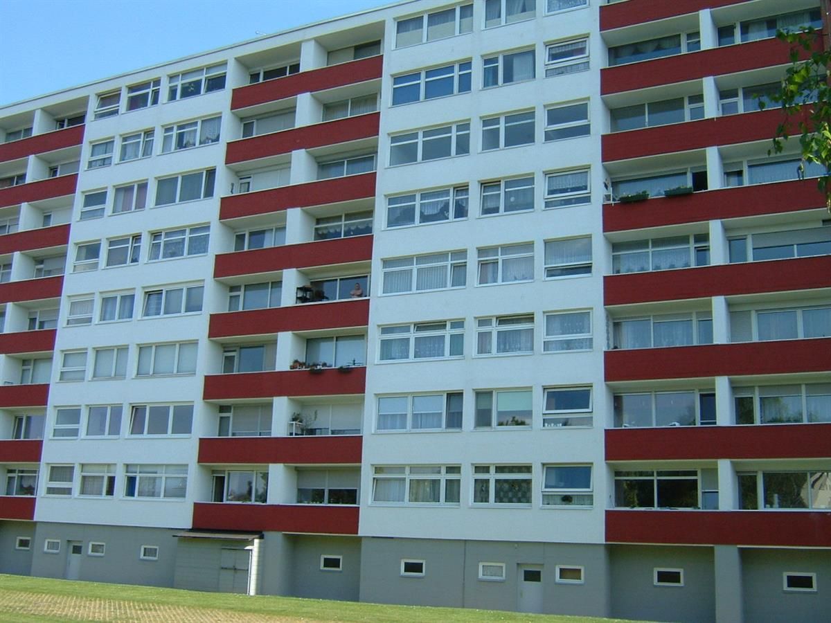 Ein großes weißes Gebäude mit roten Balkonen und Fenstern