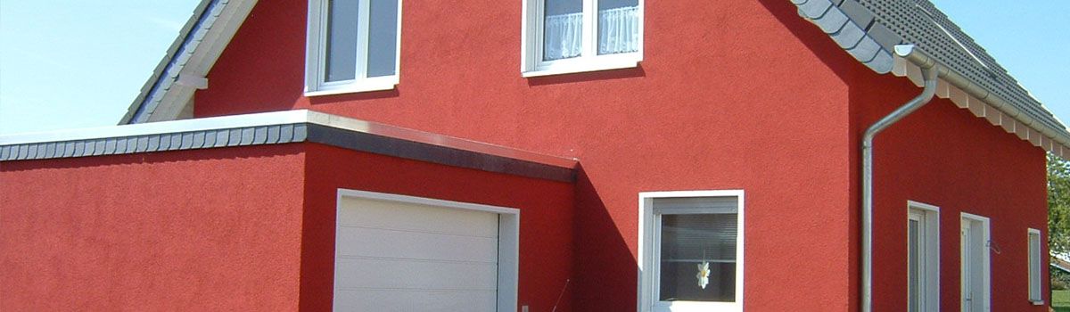 Ein rotes Haus mit weißen Fenstern und einer Garage