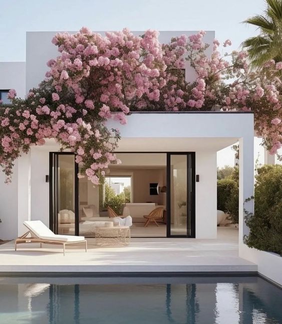 Una casa blanca con flores rosas y una piscina.