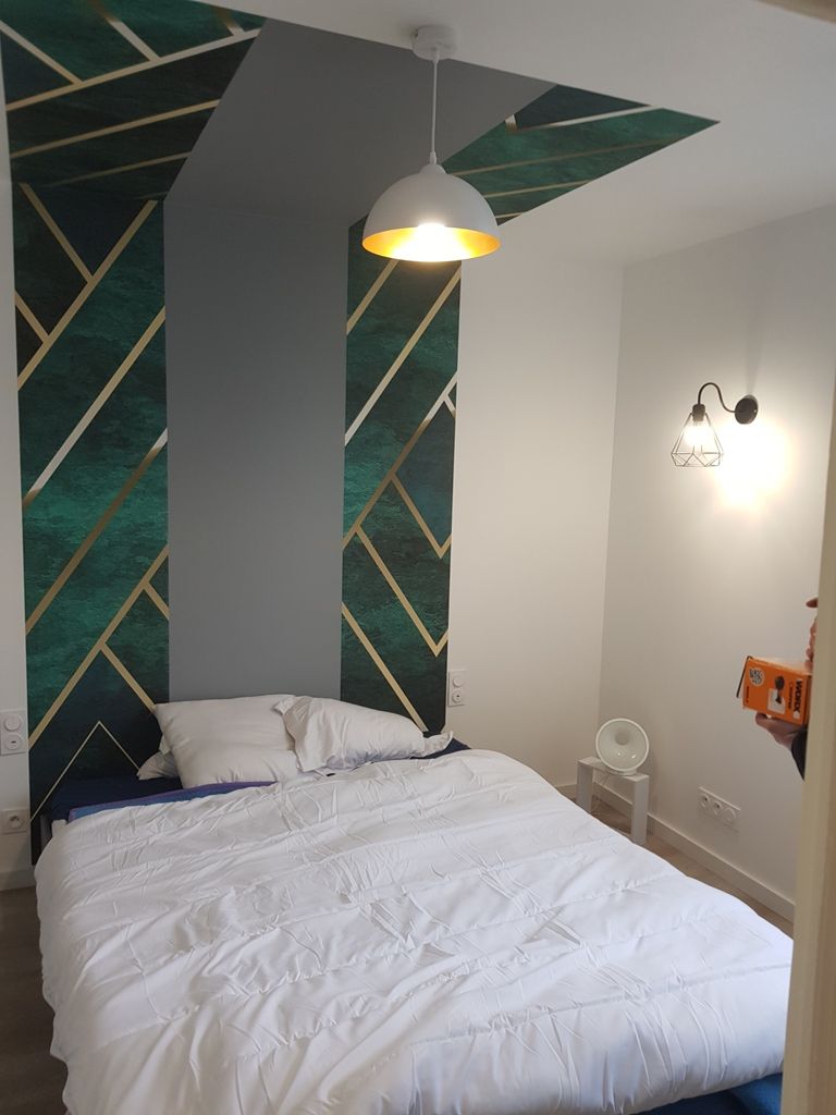 Un lit devant un mur avec du papier peint