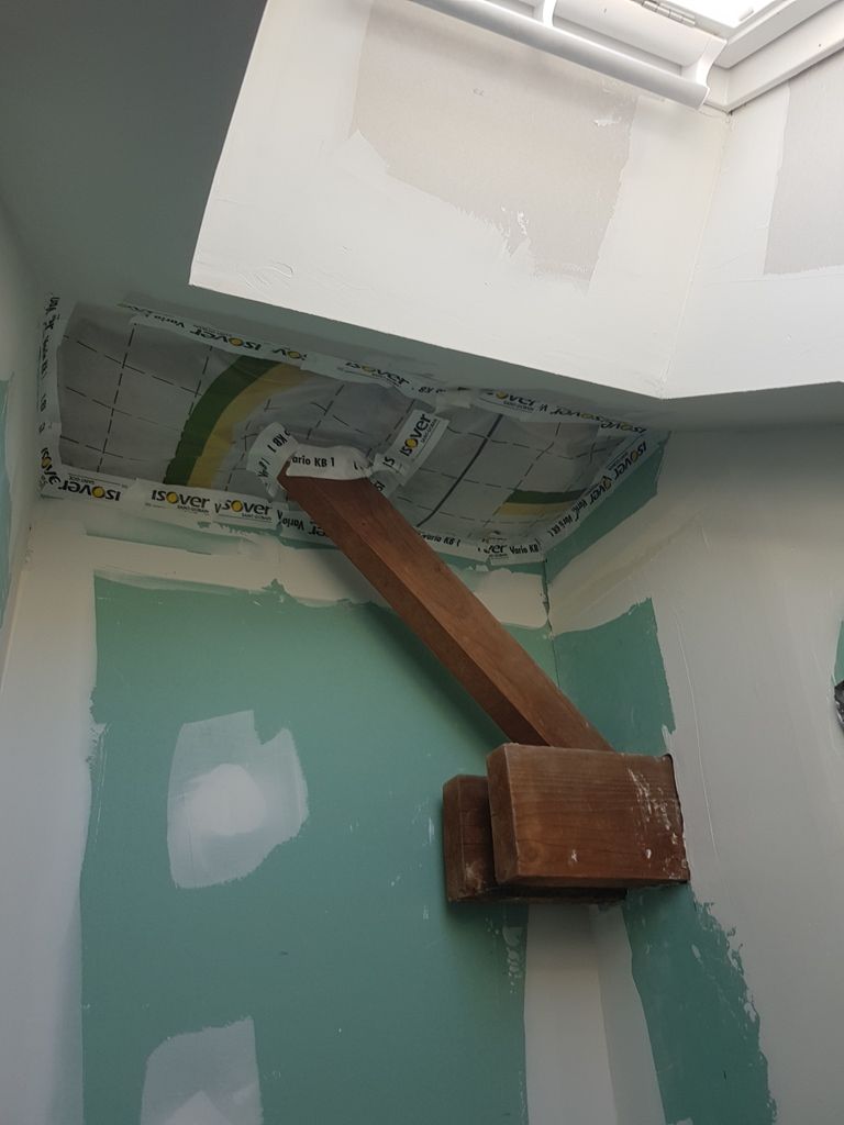 Une poutre en bois qui sort d'un mur et un mur de couleur vert pâle derrière cette poutre