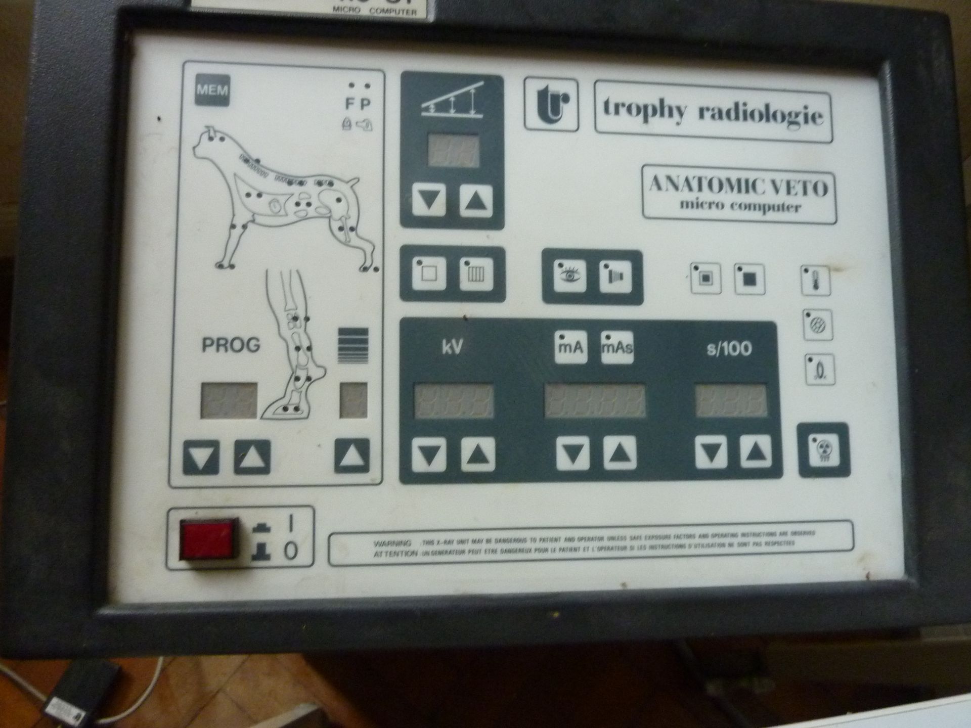 Panneau de commande pour appareil de radiographie vétérinaire. Face blanche avec bordure noire, boutons et réglages pour la radiographie animale.