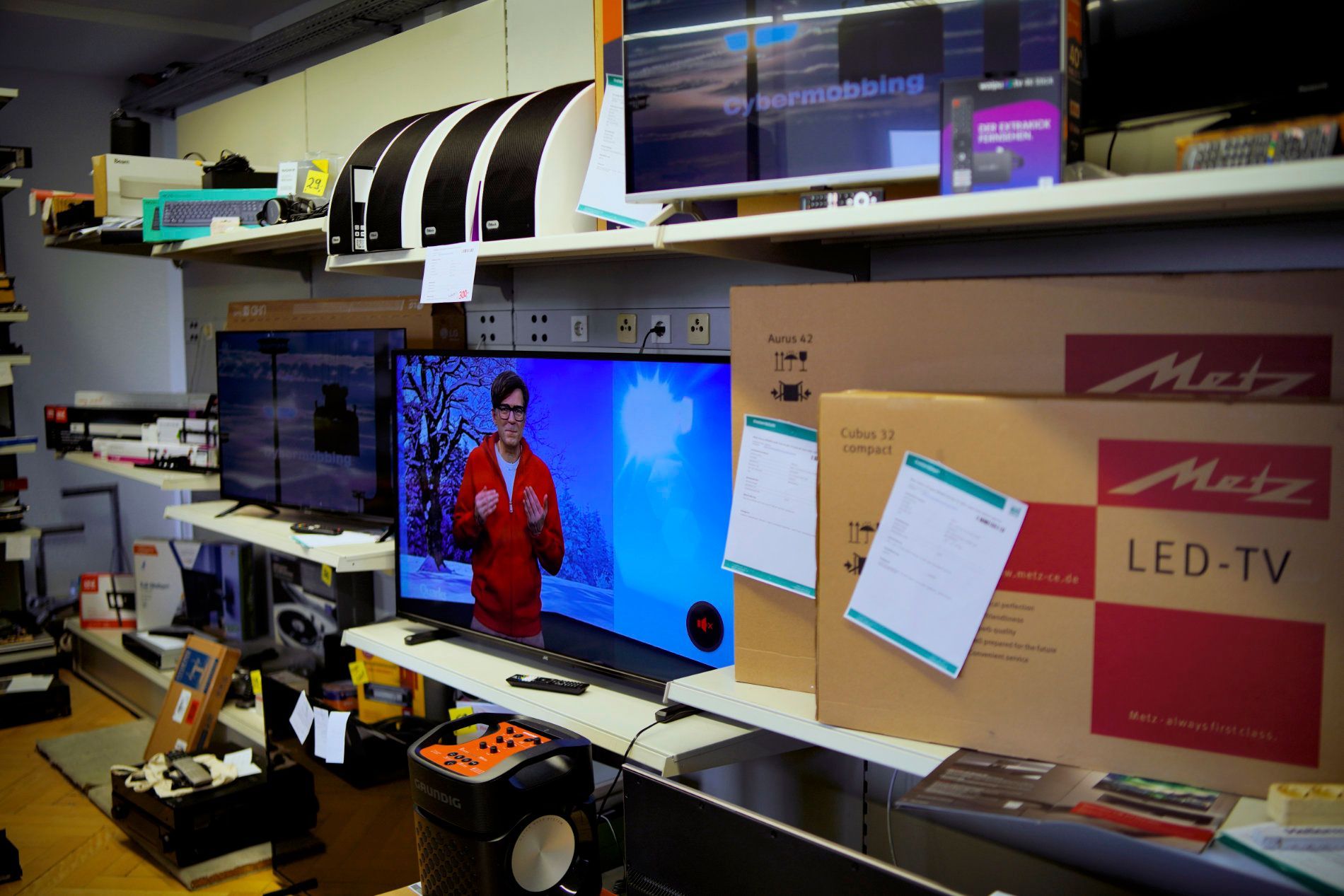 In den Regalen eines Einzelhandelsgeschäfts werden verschiedene Flachbildfernseher und verpackte LED-Fernseher der Marke Metz ausgestellt.