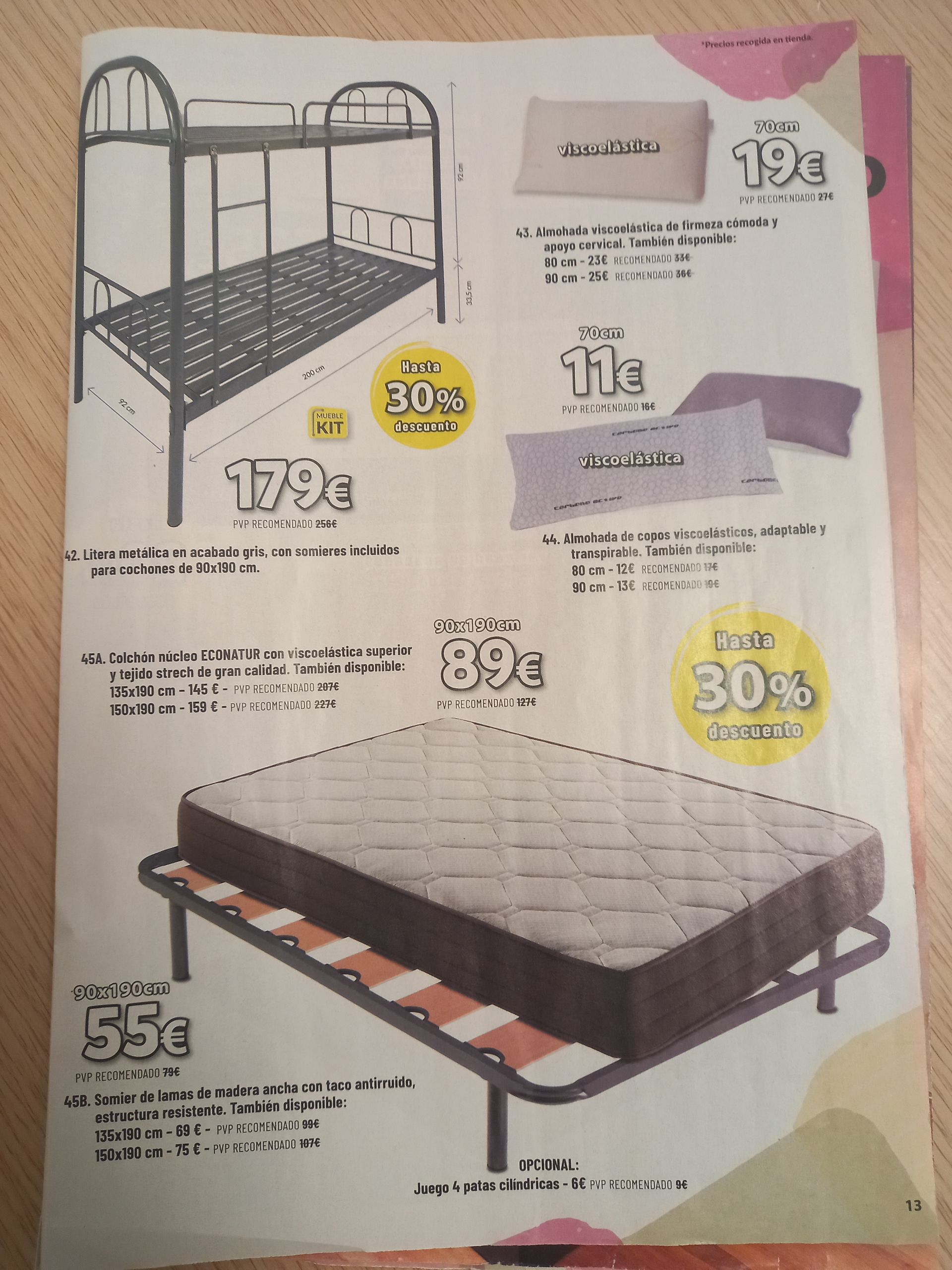 Un folleto publicitario de una tienda de muebles que muestra una litera de metal, un colchón, somieres y almohadas con precios y etiquetas de descuento.