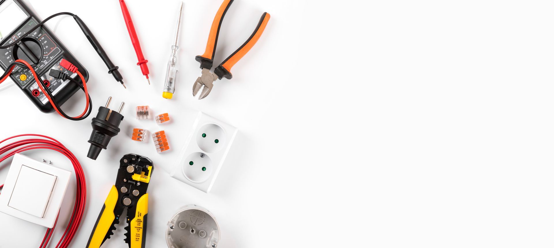 Outils et fils électriques divers disposés sur fond blanc