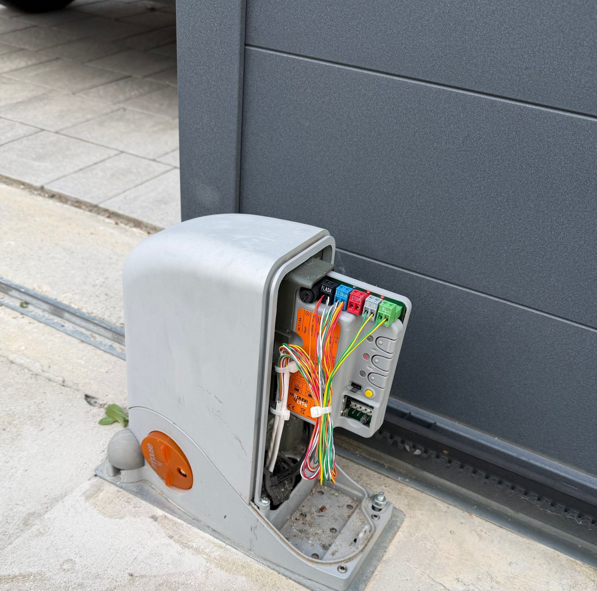 Boîte de commande électrique ouverte près d'un portail.