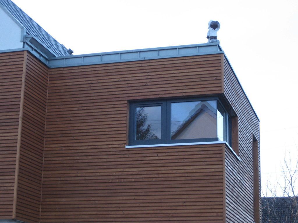 Ein braunes Gebäude mit einem schwarzen Fenster und einem Schornstein obenauf