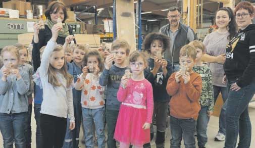 Eine Gruppe von Kindern steht in einem Raum nebeneinander und hält ihre Hände hoch.