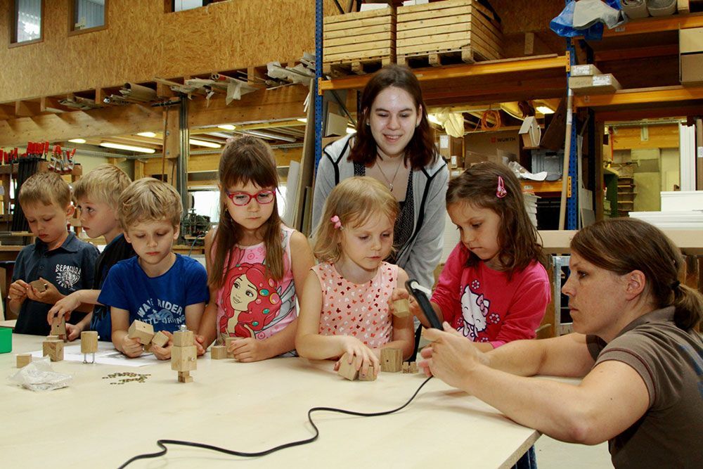 Eine Gruppe von Kindern sitzt um einen Tisch und spielt mit Holzklötzen
