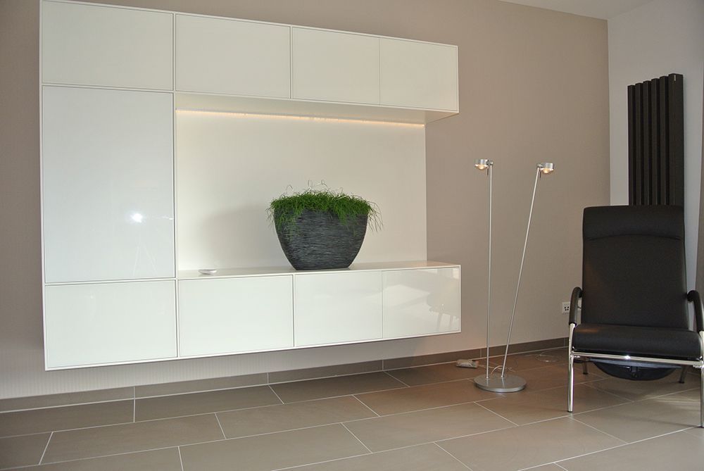 Ein Wohnzimmer mit weißen Schränken und einem schwarzen Stuhl