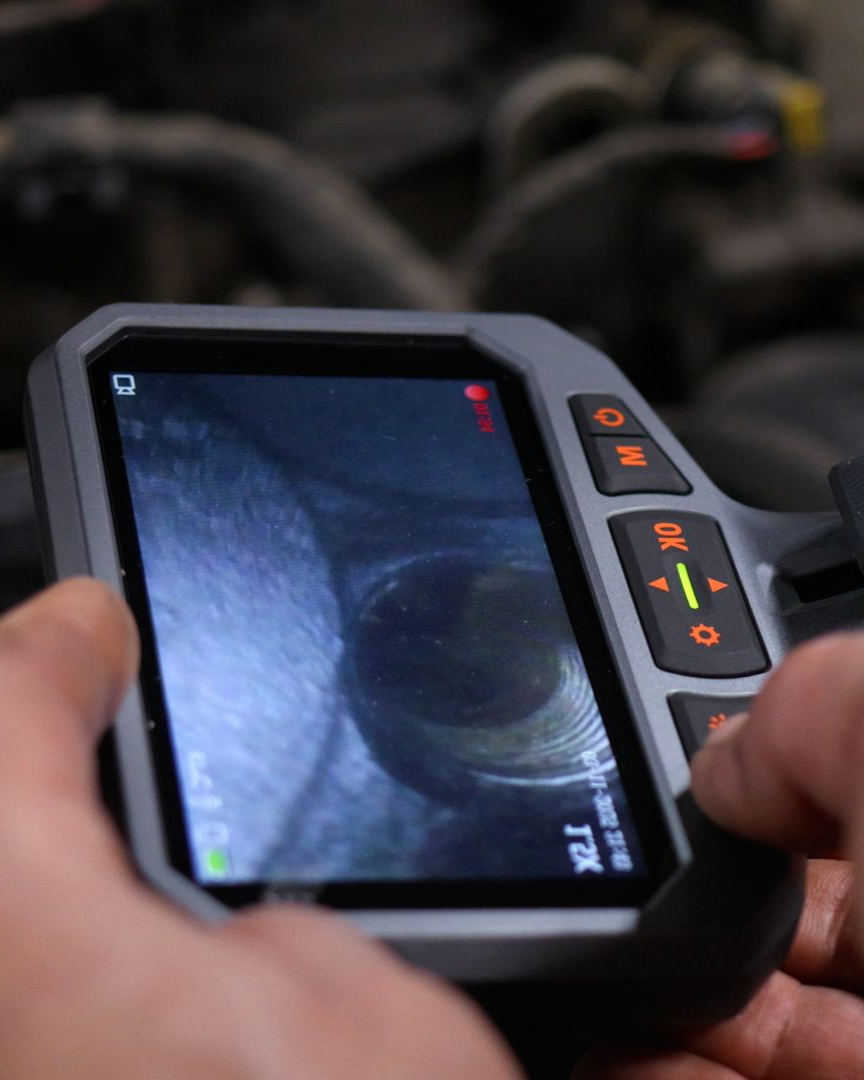 Une personne tenant une caméra de diagnostic affichant une vue rapprochée d'un tuyau.