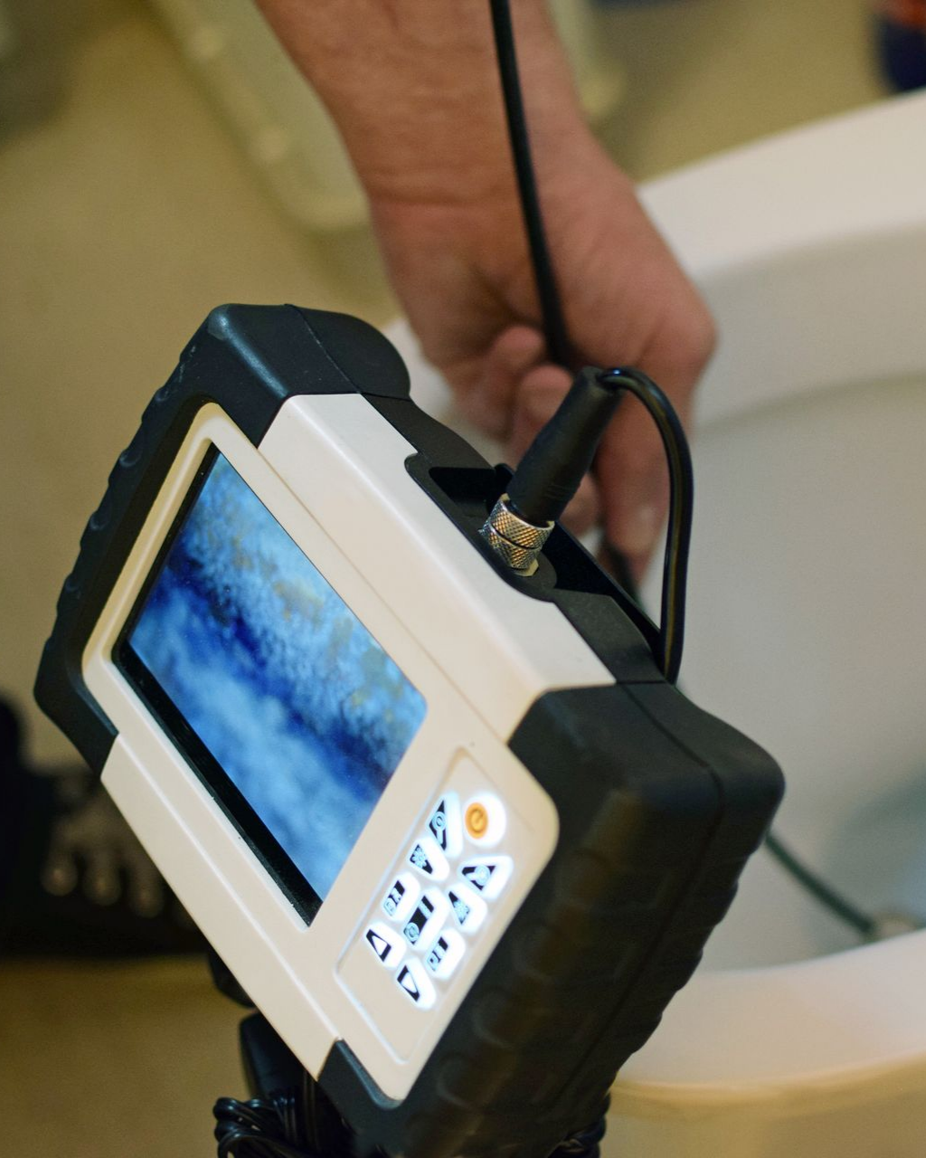 Une caméra d'inspection portative, munie d'un écran et de boutons, permet de scruter l'intérieur de la cuvette des toilettes.