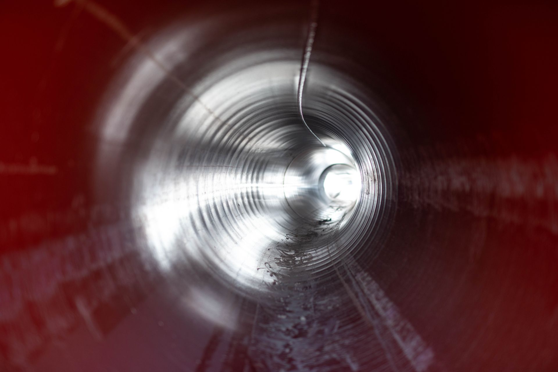 Vue intérieure d'un tuyau ondulé rouge et argenté.
