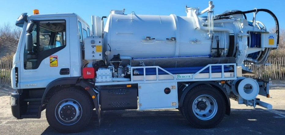 Camion aspirateur blanc stationné sur la route.