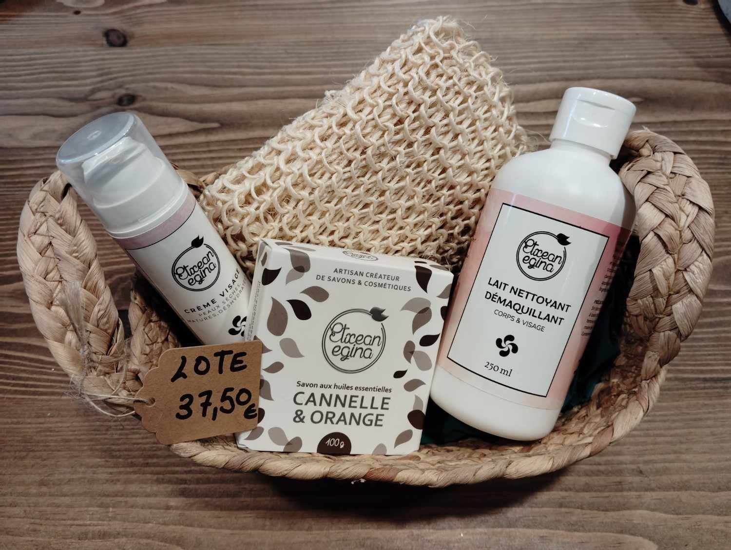 Una cesta de regalo que contiene una pastilla de jabón, una botella de limpiador, una crema facial y un guante de baño, con la etiqueta 