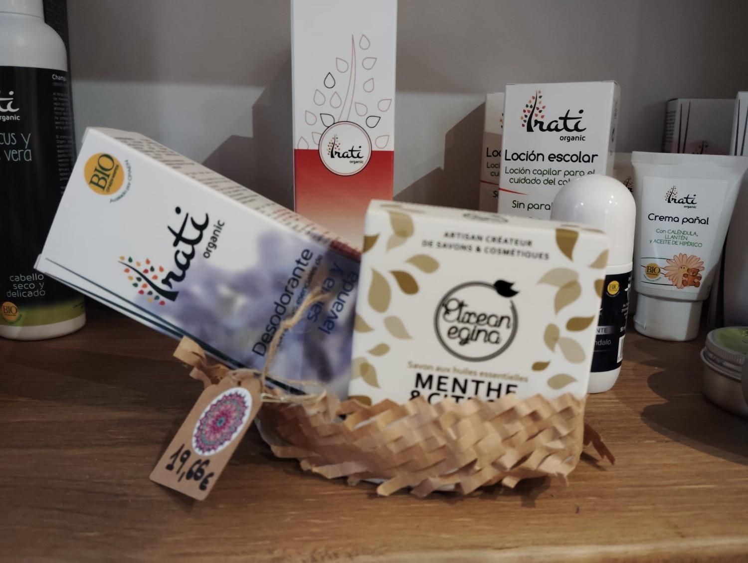 Una cesta de regalo que contiene desodorante de la marca Irati, una caja de jabón Menthe Poivrée y otros productos para el cuidado de la piel en un estante de madera.