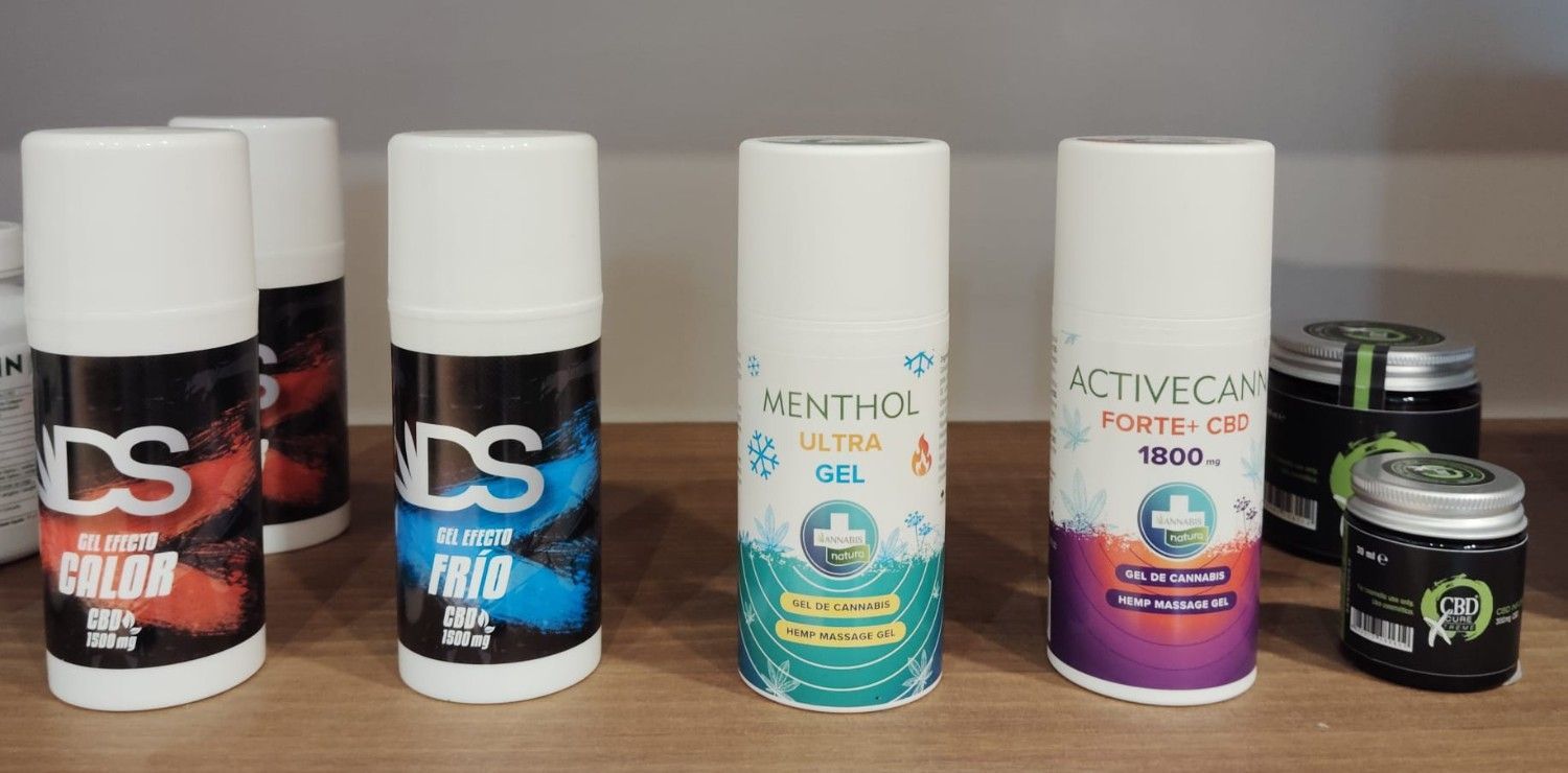 Un estante con varios frascos cilíndricos blancos con atomizador y pequeños tarros negros de productos medicinales o de bienestar.