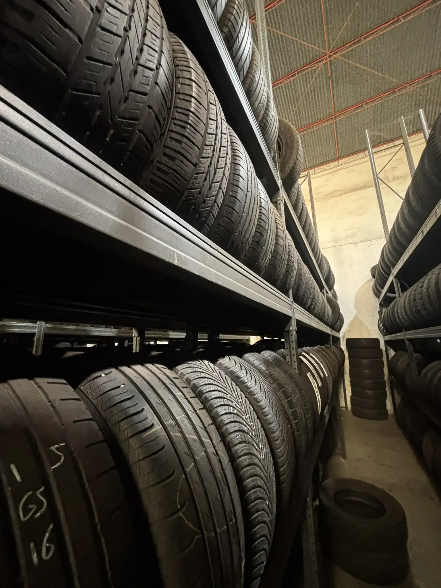 Filas de neumáticos apiladas en estantes dentro de un almacén.