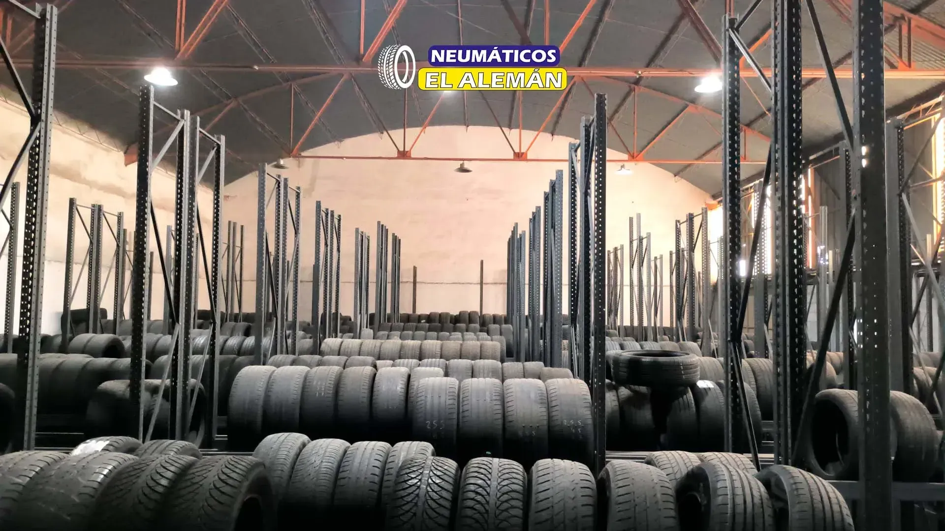 Neumáticos apilados en estantes dentro de un almacén con el logotipo 