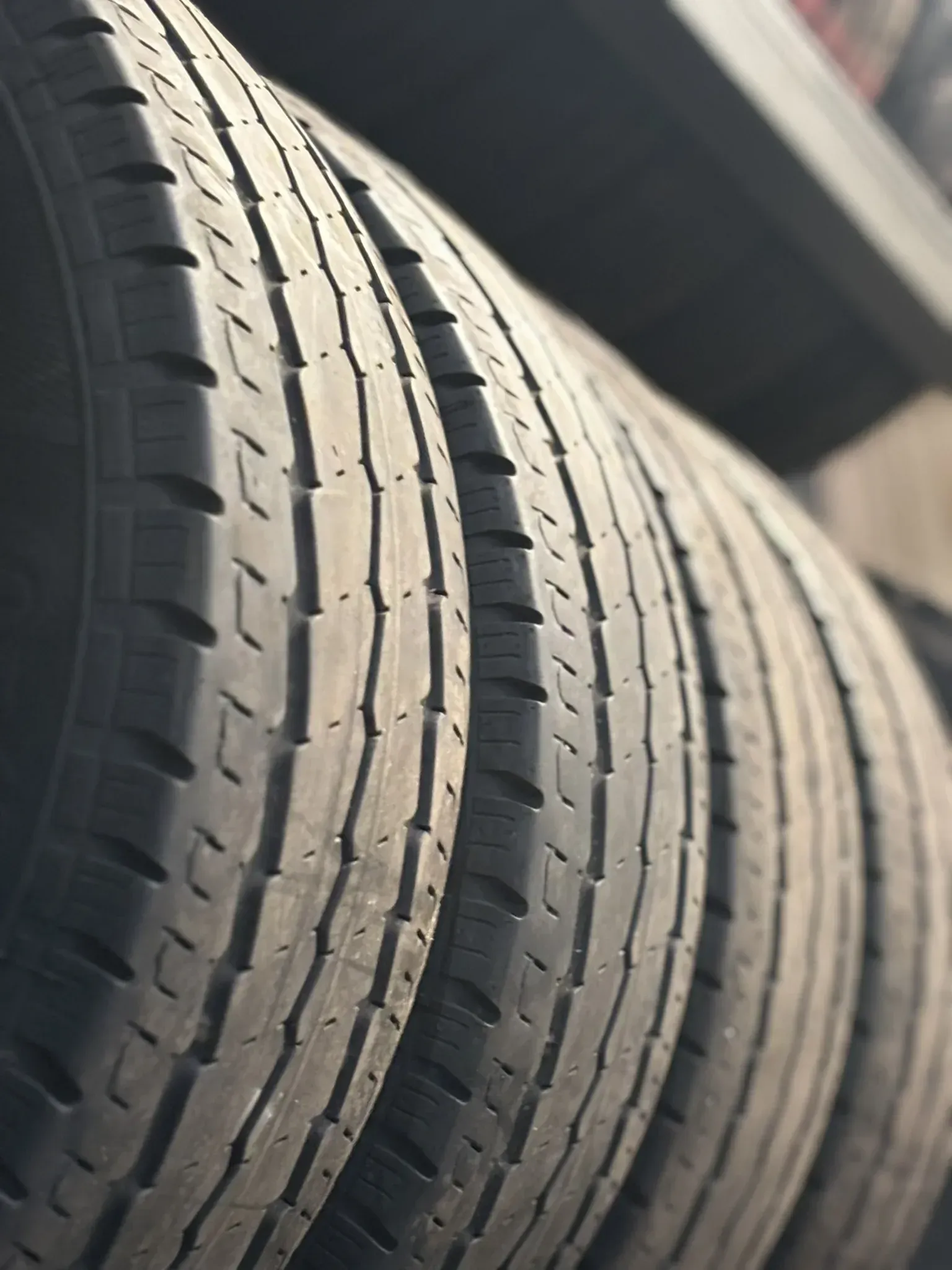 Neumáticos apilados verticalmente, mostrando las bandas de rodadura y el perfil lateral, bajo luz natural.