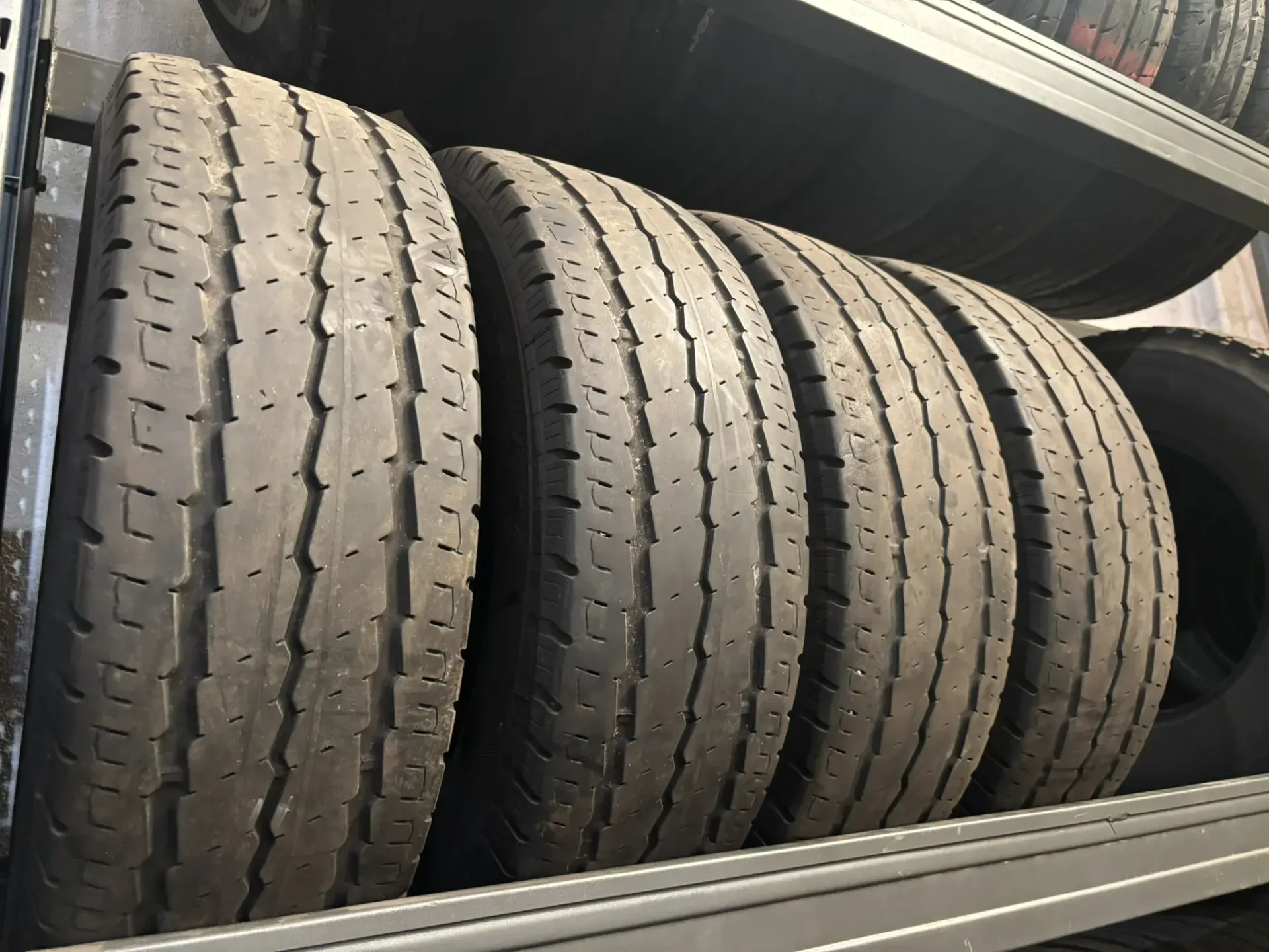 Pila de neumáticos usados ​​en un estante de metal en un garaje.