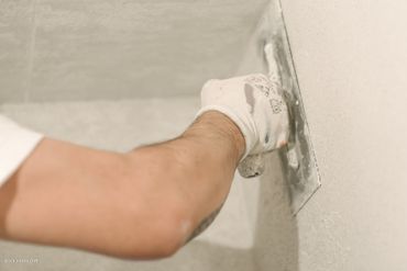 Person spachtelt eine Wand ab