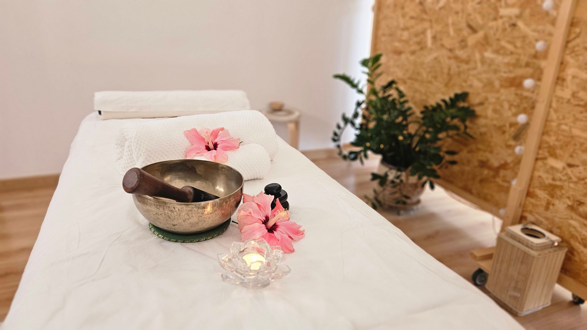 Juego de mesa de masaje para tratamiento de spa con cuenco cantor y flores.