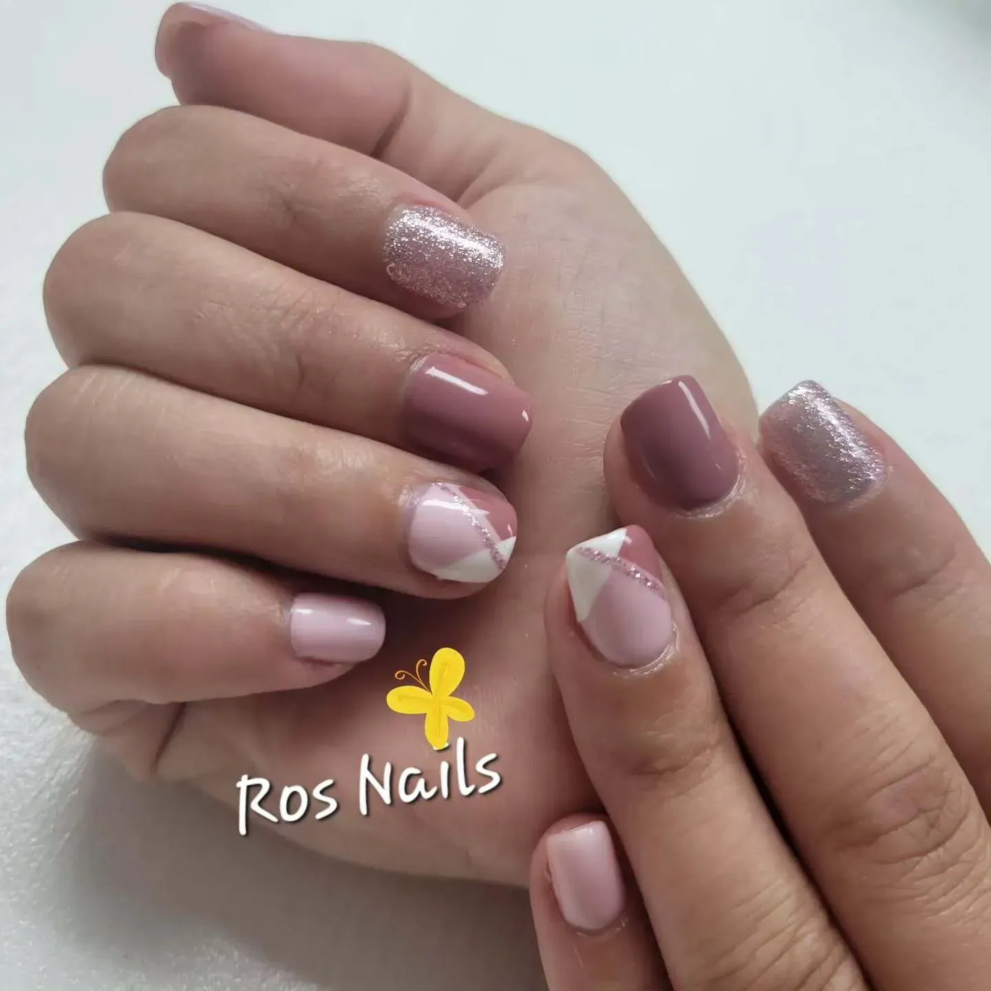 Pies en sandalias blancas con uñas color lavanda, una de ellas acentuada con un diseño de hojas negras.