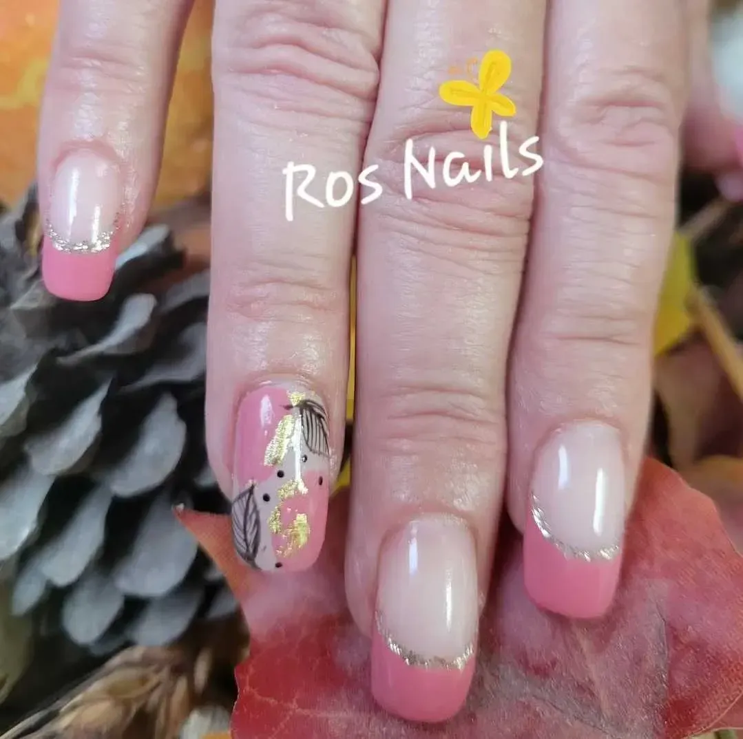 Par de pies con uñas de punta francesa, apoyados sobre una superficie texturizada, con una flor rosa.