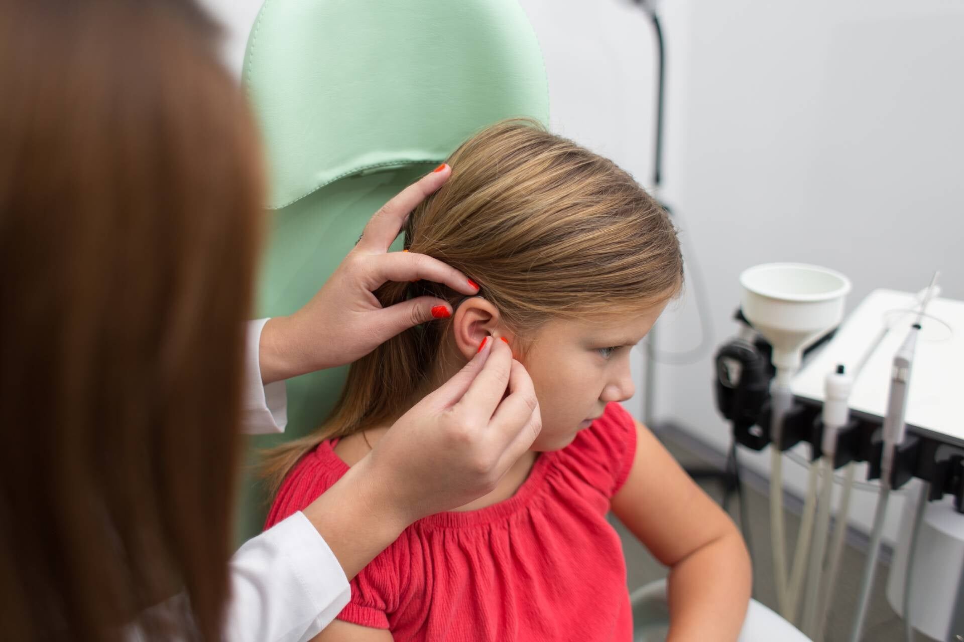 Médico examina o ouvido de uma menina em uma clínica. A menina parece preocupada.