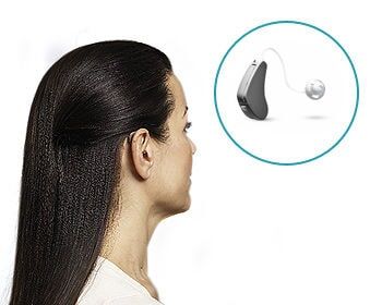 Mulher com cabelos escuros, vista de perfil, perto de um aparelho auditivo.