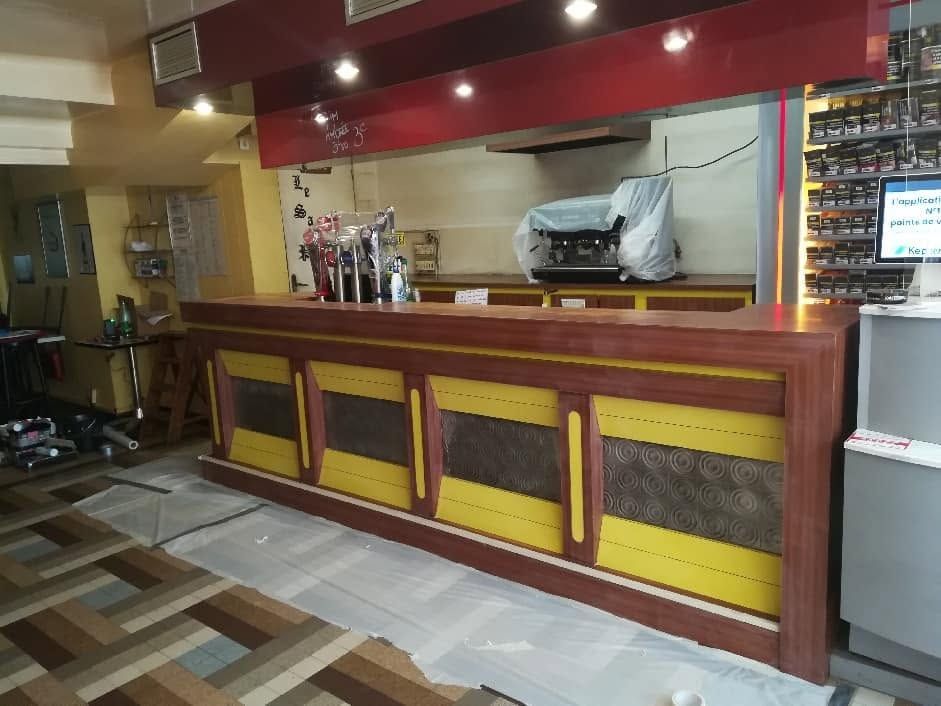 Comptoir de bar vide dans un restaurant aux panneaux rouges et jaunes.