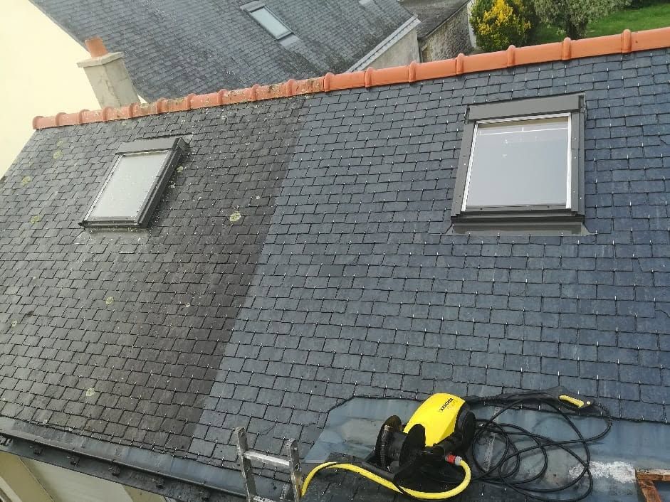 Toiture en ardoise, deux puits de lumière et un outil électrique jaune sur le bord inférieur.