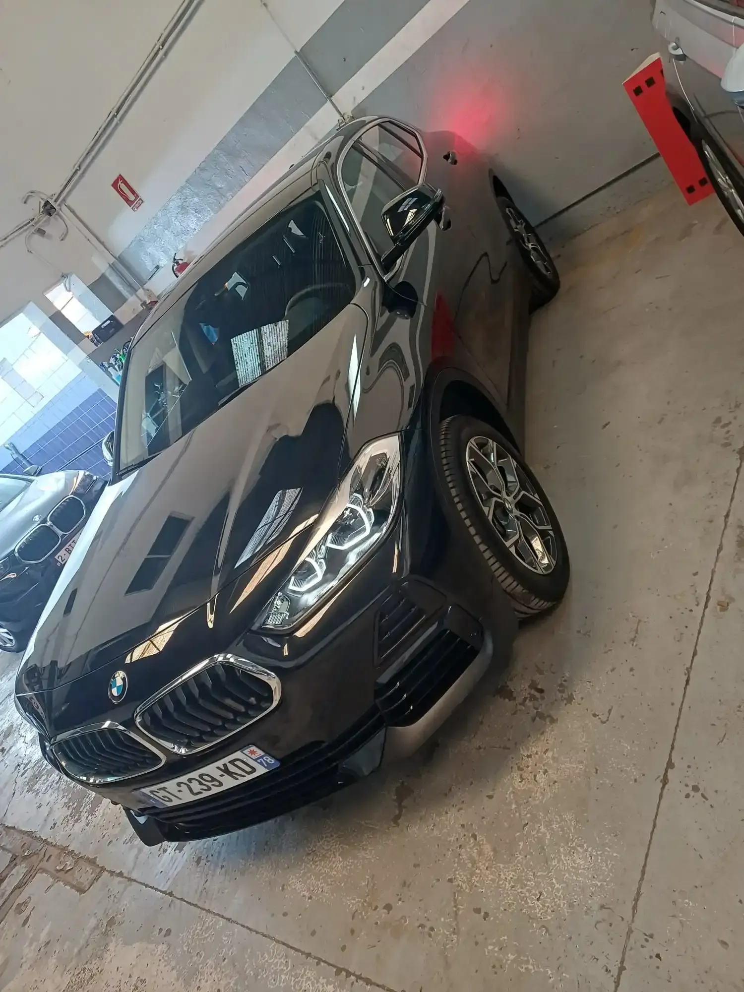 Sedán BMW negro estacionado en un garaje, visto desde el ángulo frontal izquierdo.