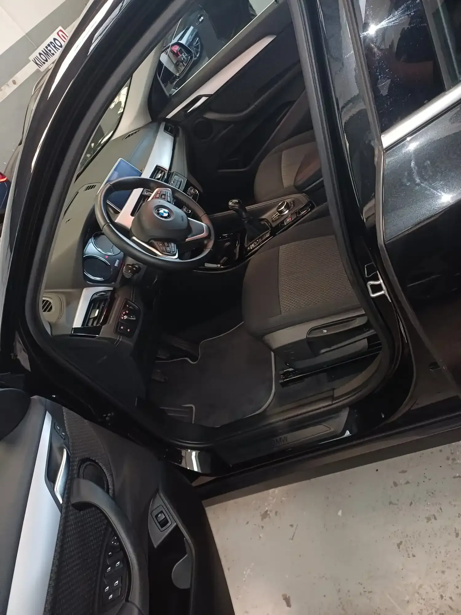 Puerta del coche abierta que deja ver el interior y el volante de un BMW negro, aparcado en el interior.