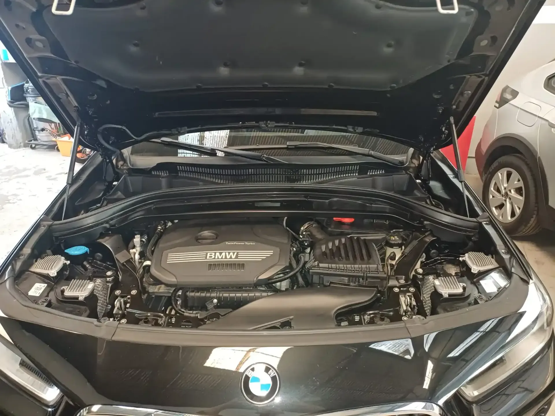 Capó abierto de un BMW que deja ver el compartimento del motor en un garaje.