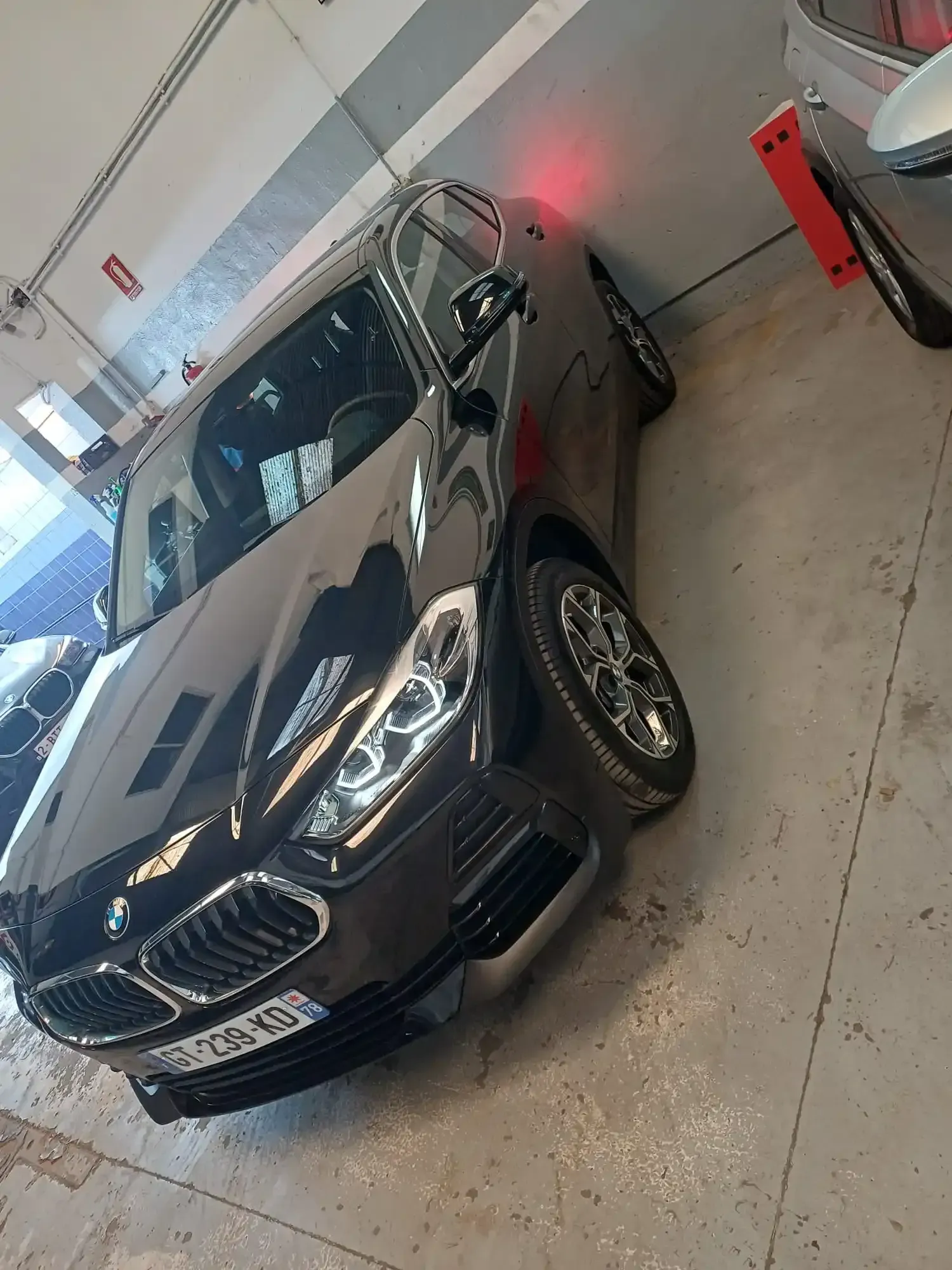 SUV BMW negro estacionado en el interior de un garaje, vista frontal izquierda.