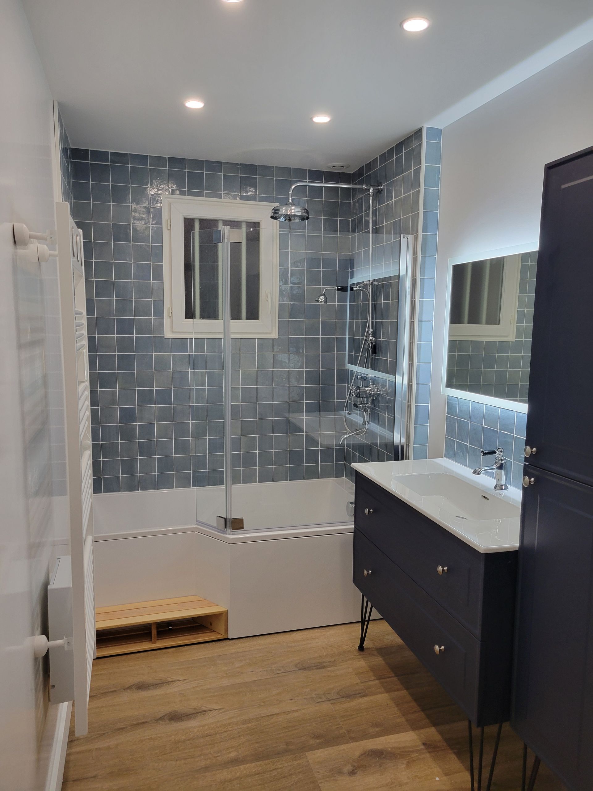 Salle de bains moderne avec meuble lavabo, miroir et douche.