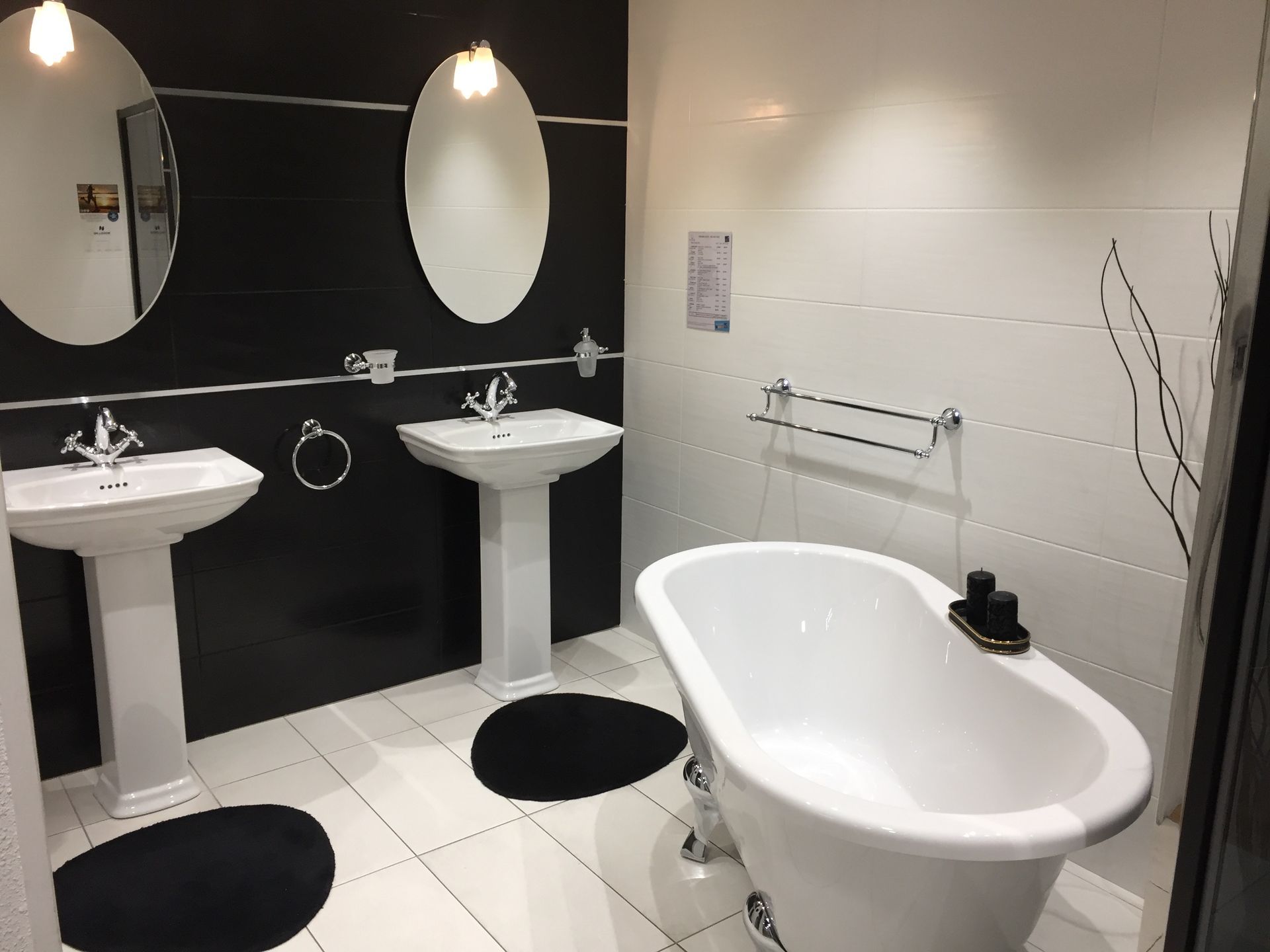 Salle de bains moderne et accessible avec deux lavabos, miroirs ovales, mur d'accent noir et baignoire blanche.