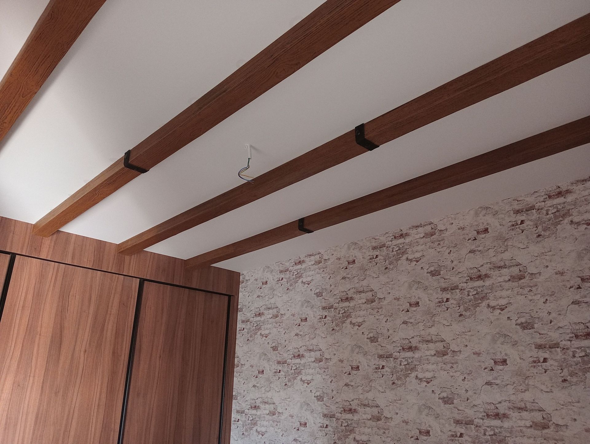 Una habitación con una pared de ladrillo y vigas de madera en el techo.