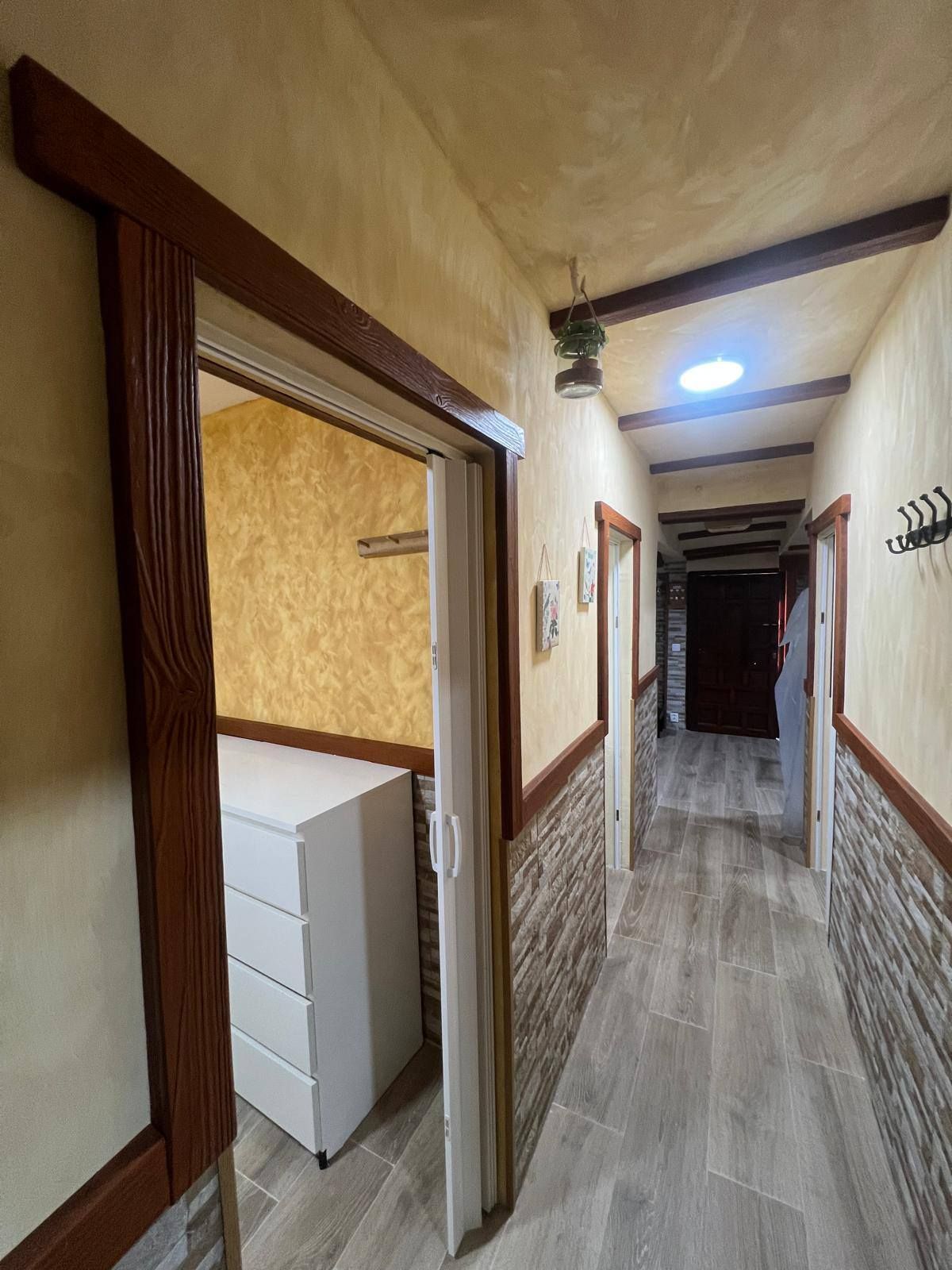 Un pasillo largo con una cómoda en el medio.