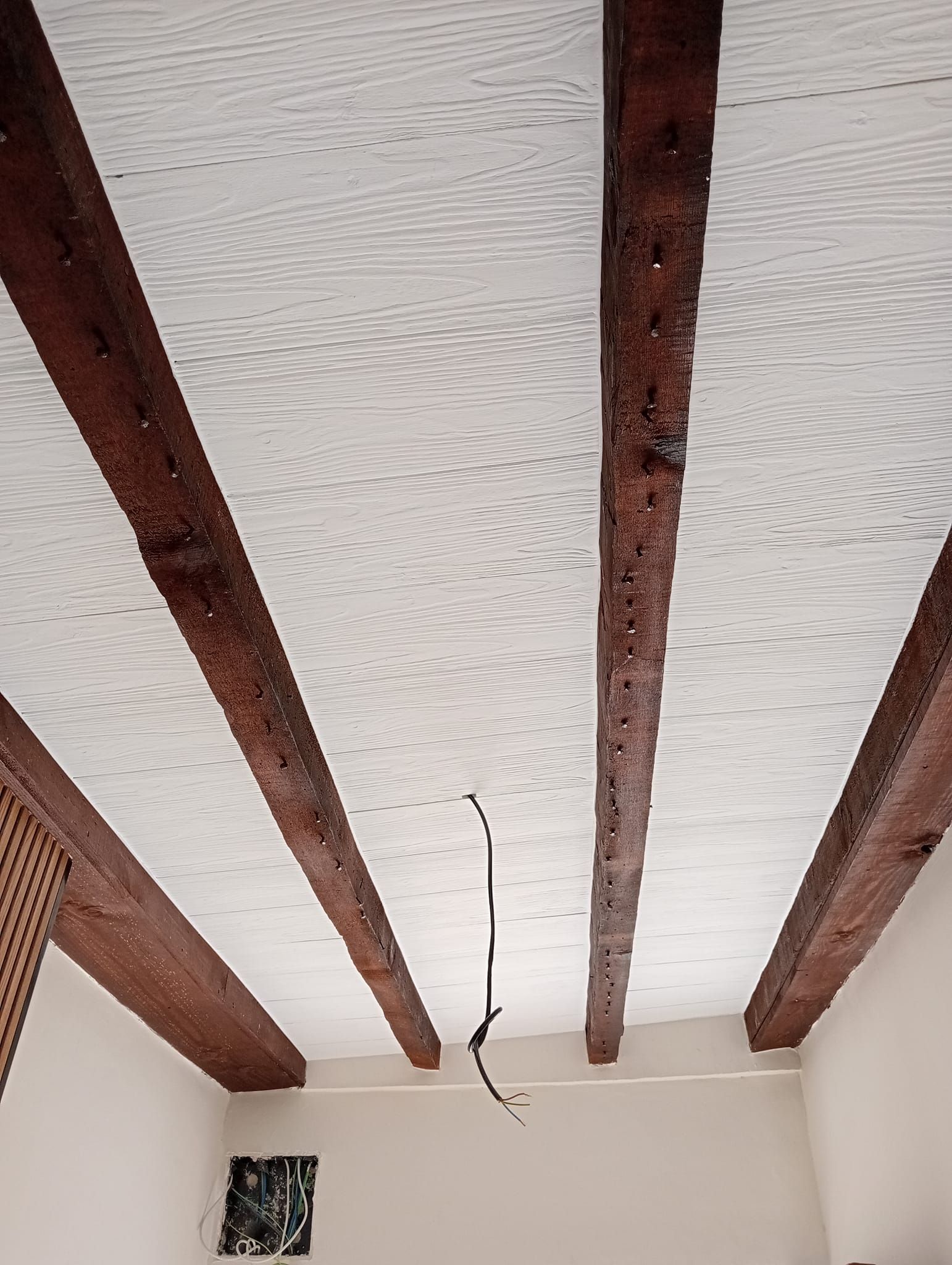 Una habitación con techo blanco y vigas de madera.