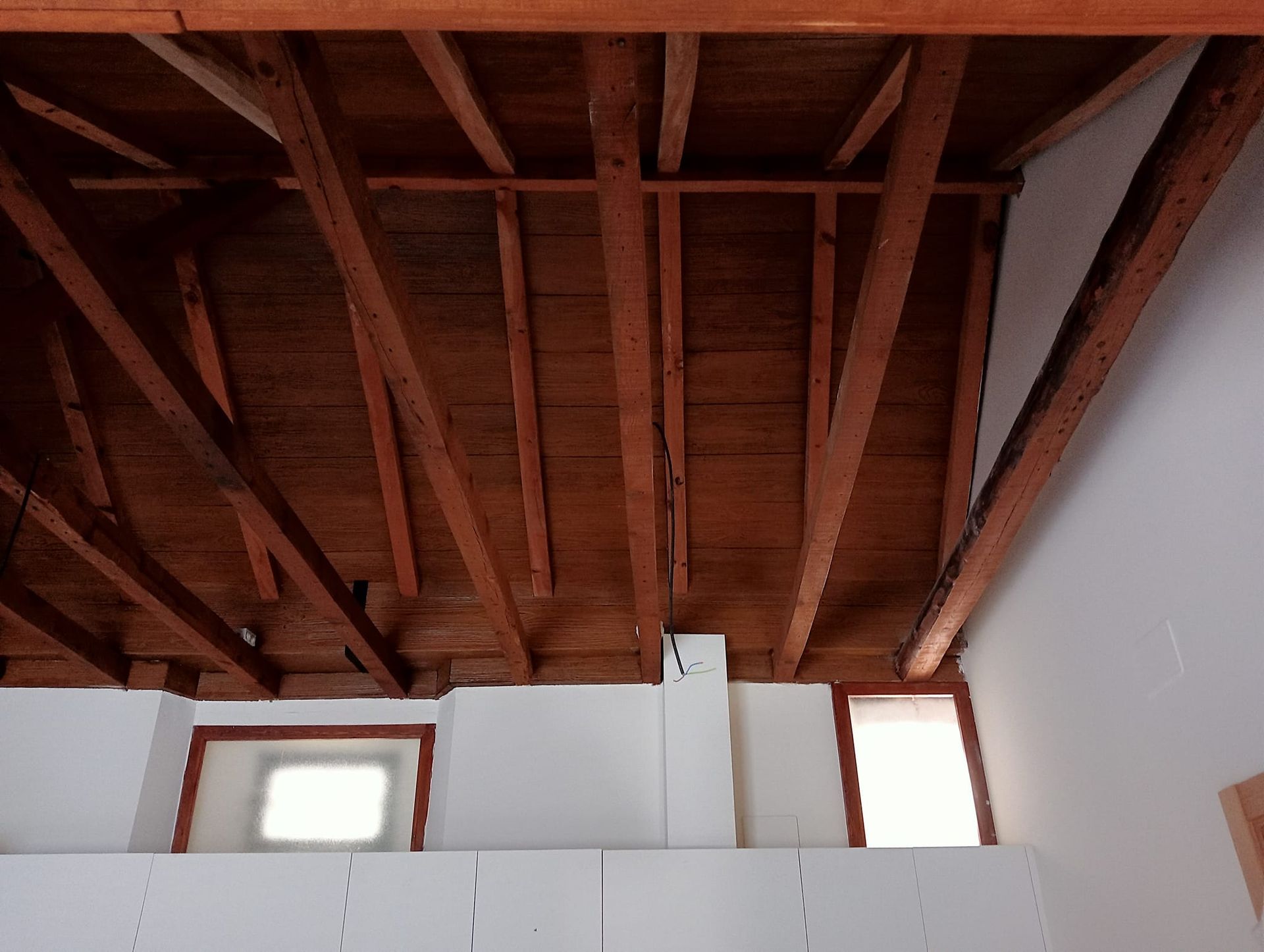 Una habitación con techo de madera y paredes blancas.