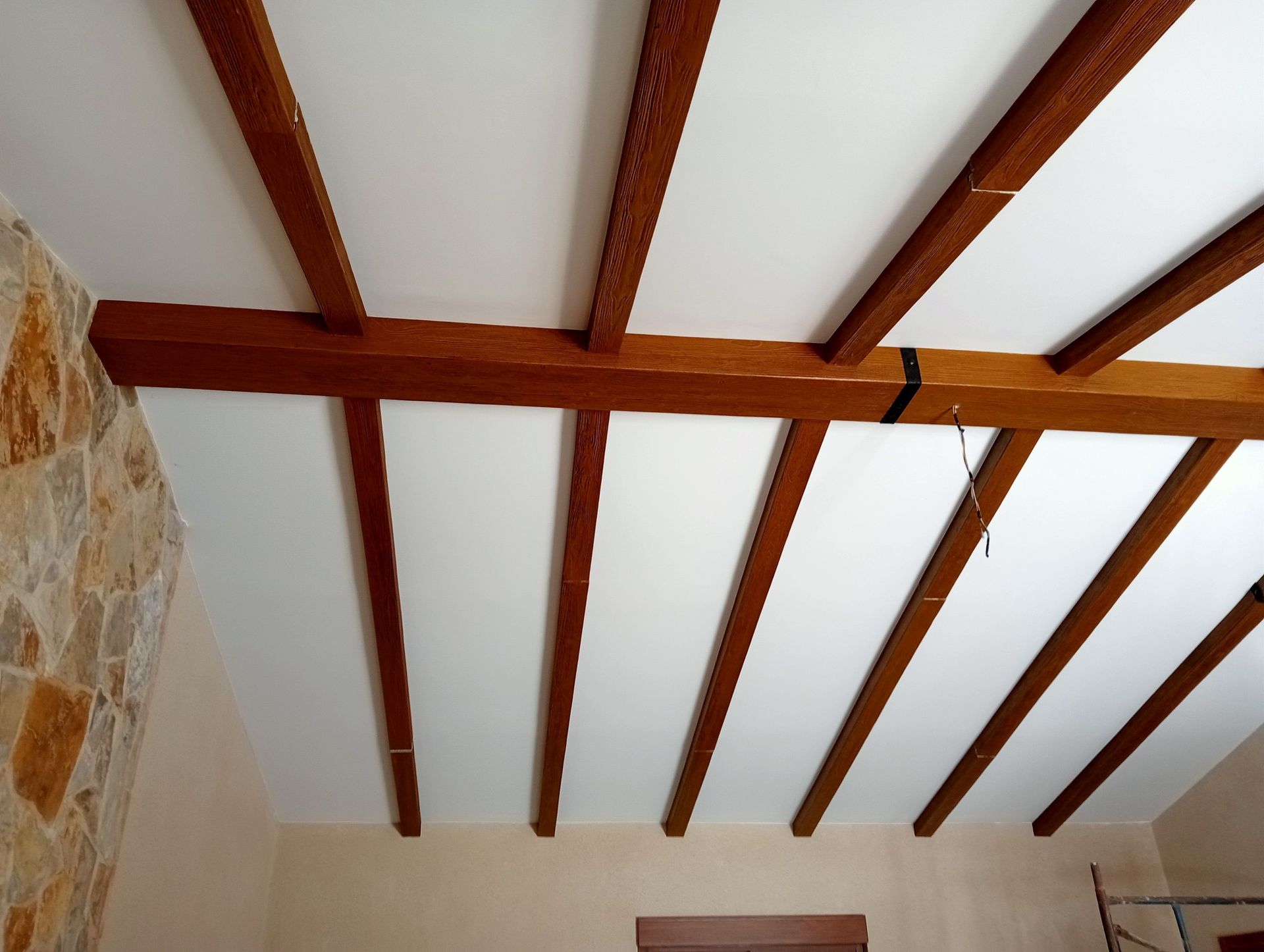 Una habitación con techo blanco y vigas de madera.