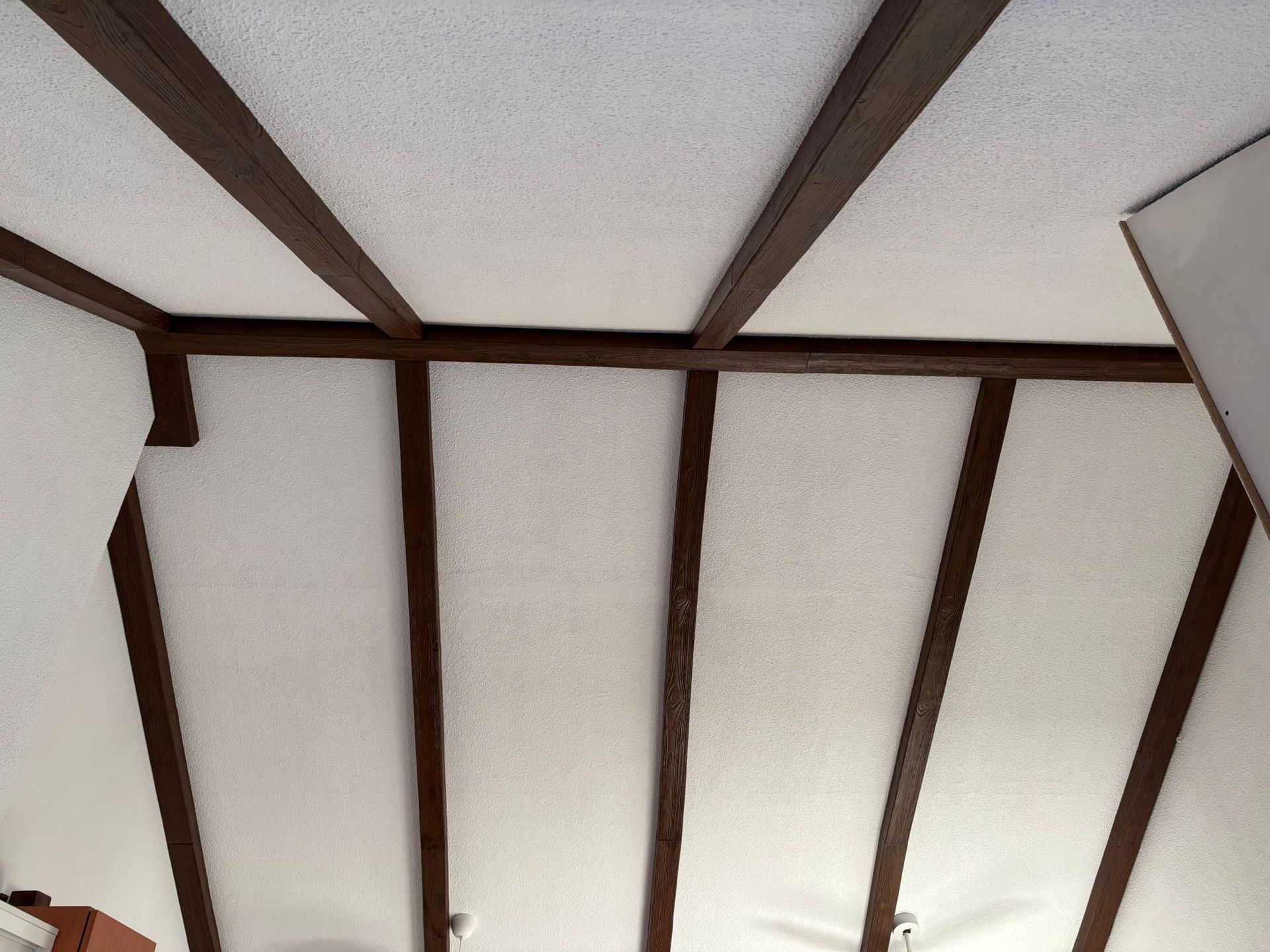 Un techo blanco con vigas marrones y un ventilador de techo.