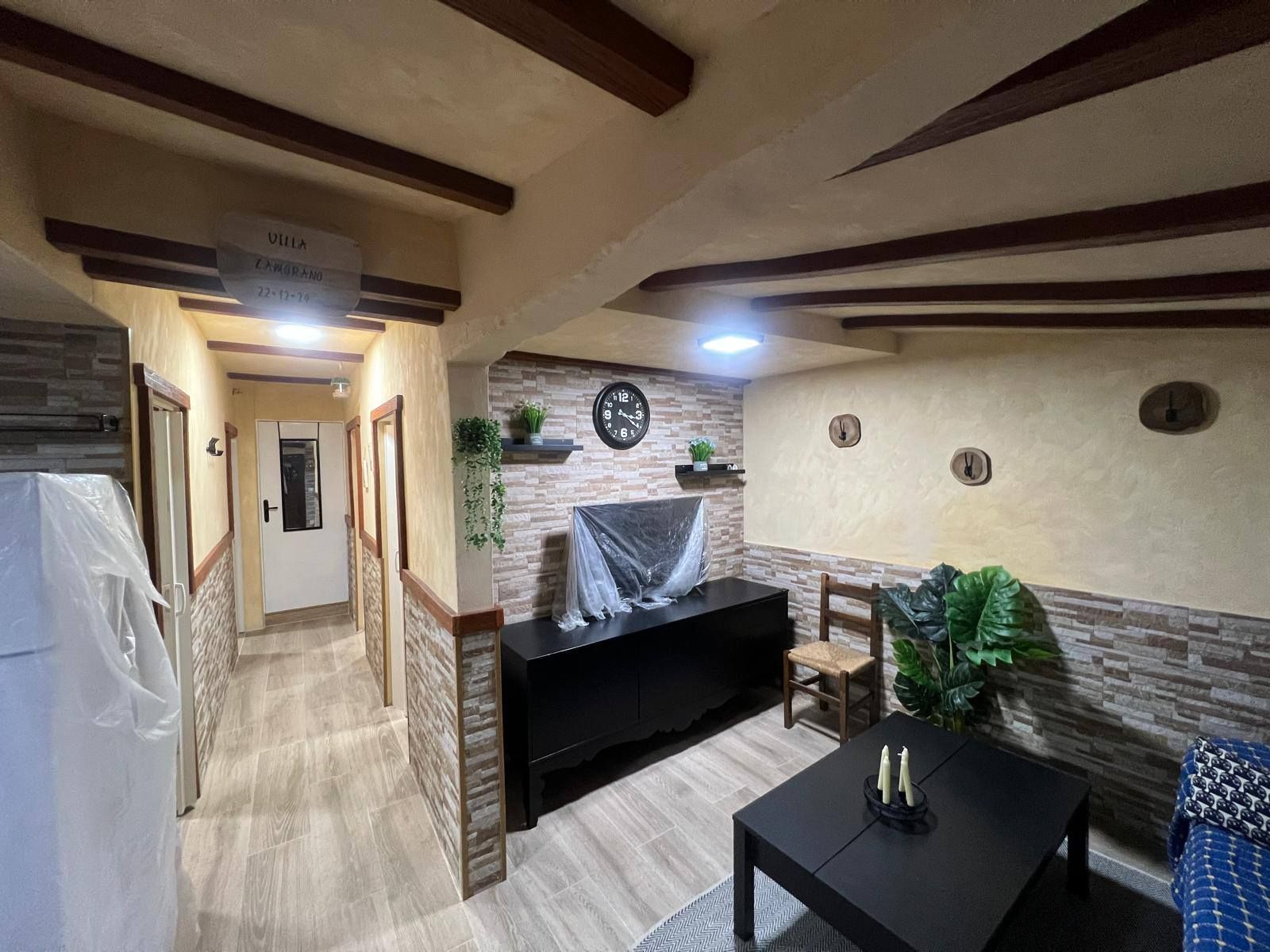 Una sala de estar con un sofá, una mesa, sillas y un refrigerador.