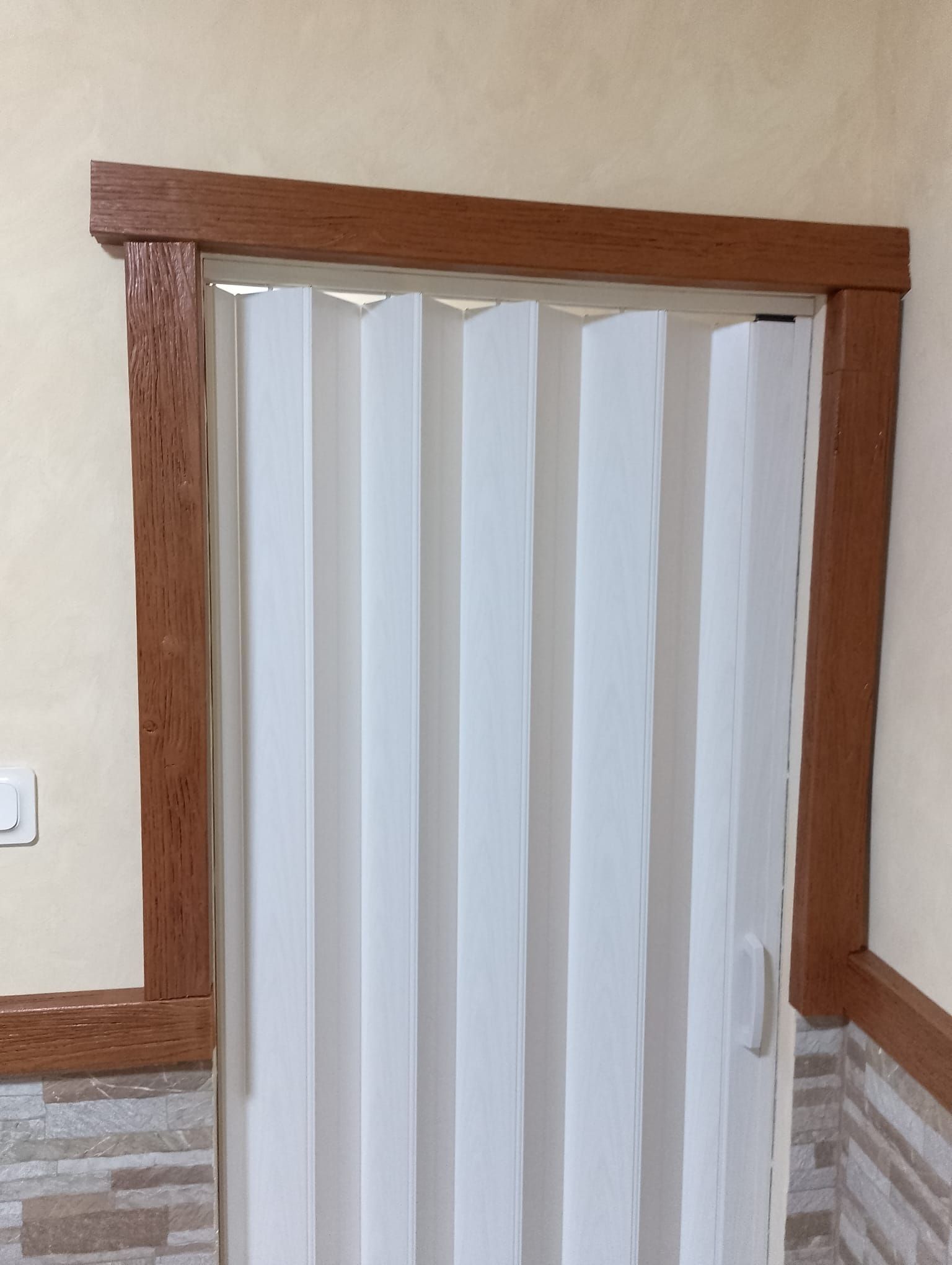 Una puerta plegable blanca con marco de madera